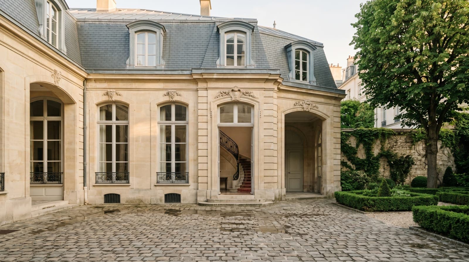 Façade d'un hôtel particulier parisien avec cour pavée et jardin
